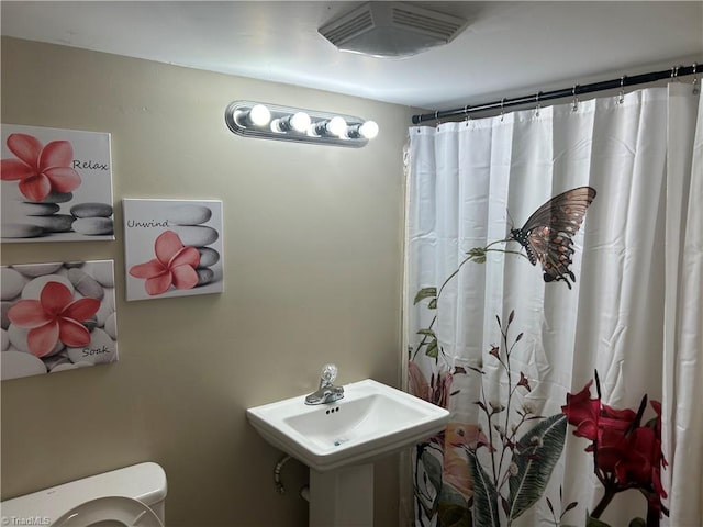 bathroom featuring sink, curtained shower, and toilet