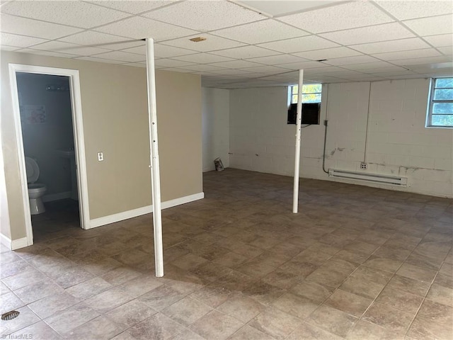 basement with a paneled ceiling and a baseboard radiator