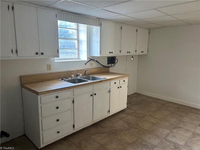 kitchen with a paneled ceiling, sink, and white cabinets