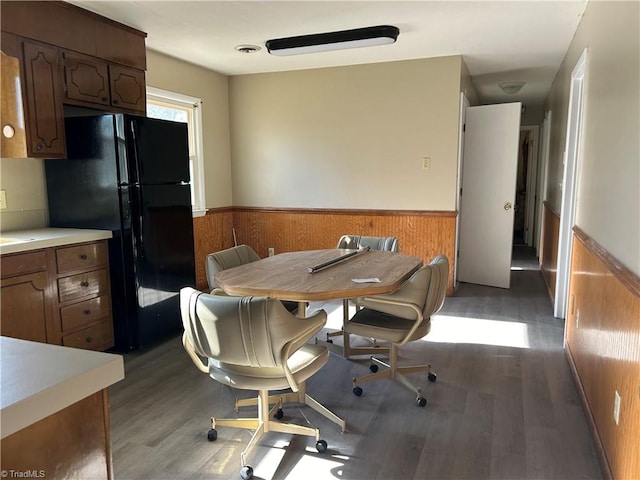 dining space with dark wood-type flooring and wood walls