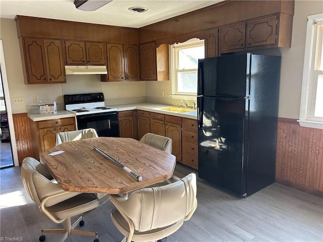 kitchen with sink, light wood-type flooring, white range with electric stovetop, and black refrigerator