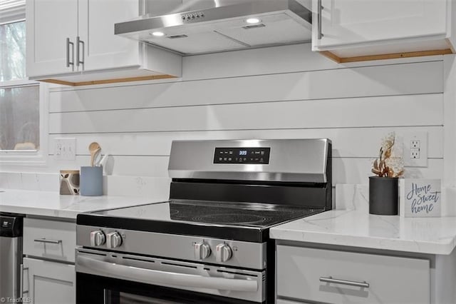 kitchen featuring wall chimney exhaust hood, white cabinetry, appliances with stainless steel finishes, and light stone countertops