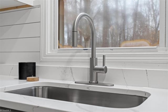 room details with sink, light stone countertops, and white cabinets