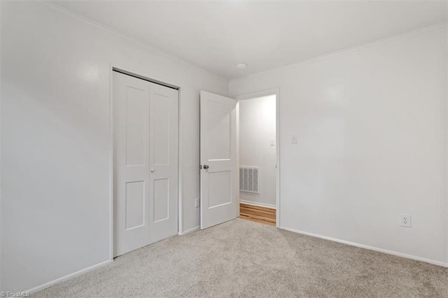 unfurnished bedroom featuring ornamental molding, light colored carpet, and a closet