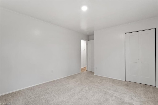 unfurnished bedroom with light carpet and a closet