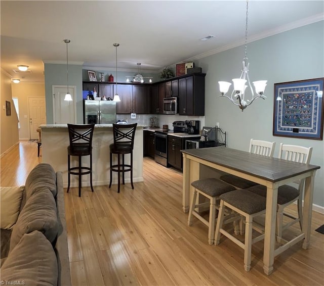 kitchen featuring a breakfast bar area, stainless steel appliances, ornamental molding, open floor plan, and light wood-type flooring