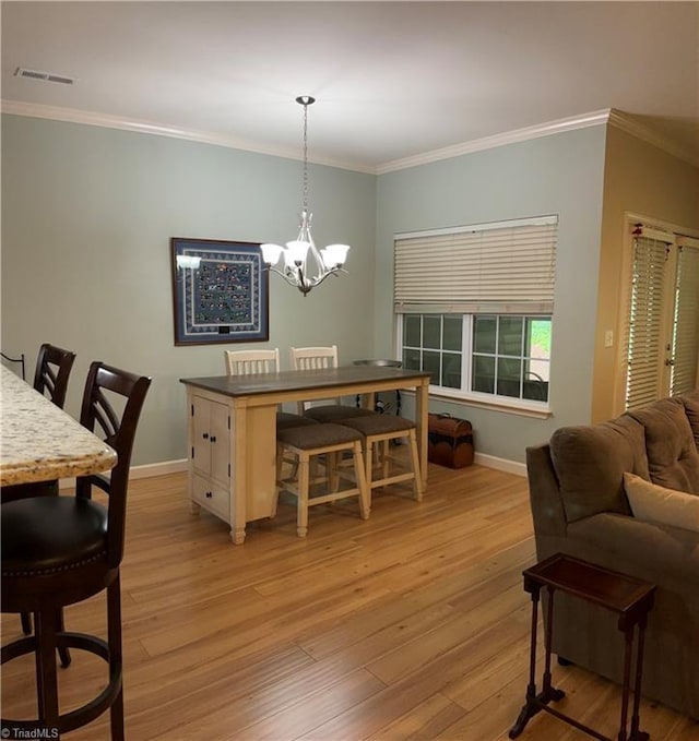 dining area featuring light wood-type flooring, baseboards, visible vents, and ornamental molding