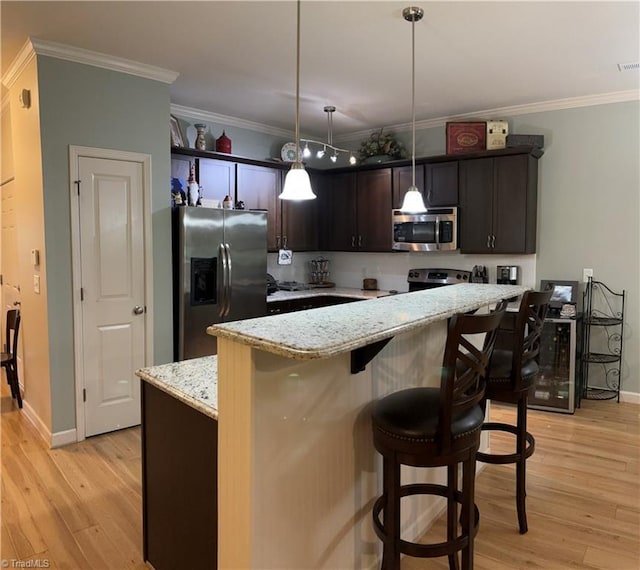 kitchen featuring stainless steel appliances, light wood-type flooring, and crown molding