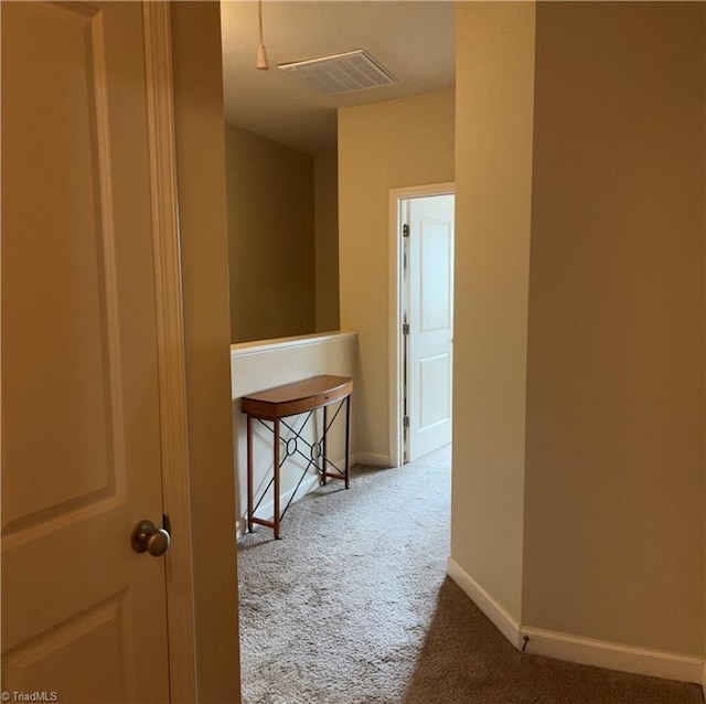 hall with baseboards, visible vents, and carpet flooring