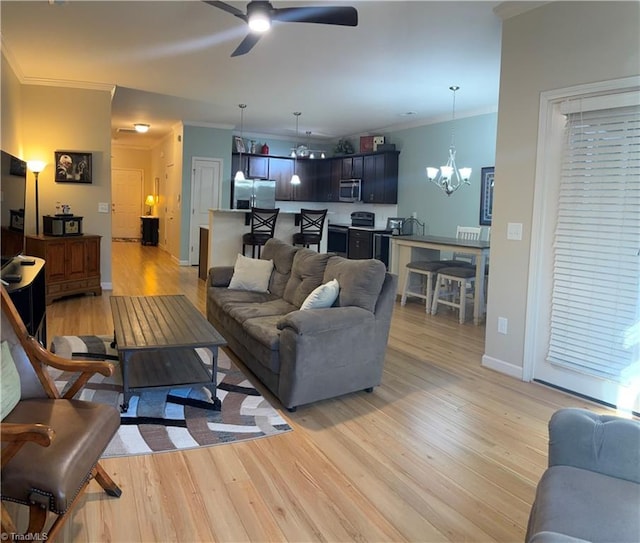 living area with light wood-type flooring, baseboards, crown molding, and ceiling fan with notable chandelier