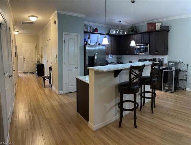 kitchen with ornamental molding, appliances with stainless steel finishes, light wood-style flooring, and a center island