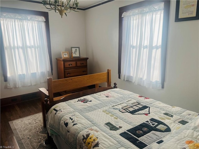 bedroom with multiple windows, dark wood-type flooring, and an inviting chandelier