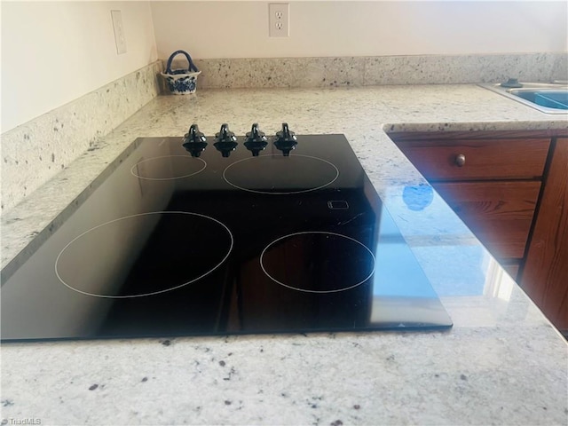 details with black electric stovetop and light stone countertops