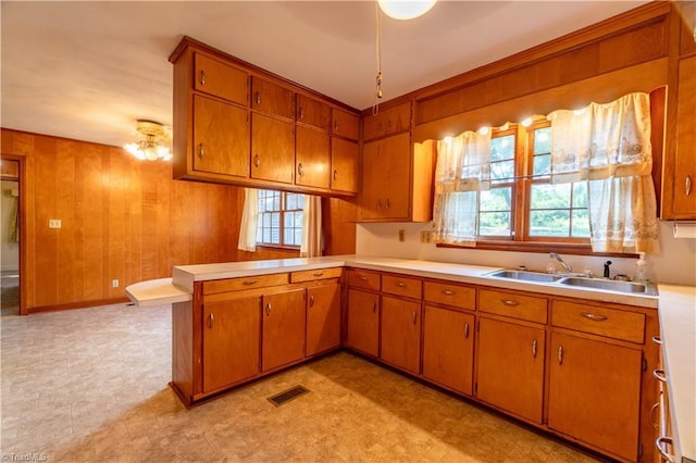 kitchen with wood walls, kitchen peninsula, and sink