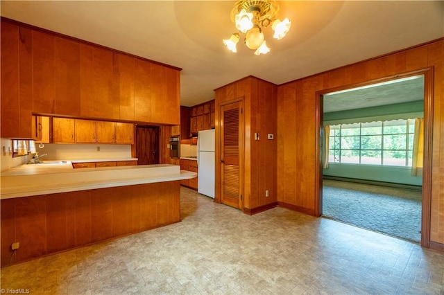 kitchen with kitchen peninsula, wood walls, a baseboard radiator, and white refrigerator