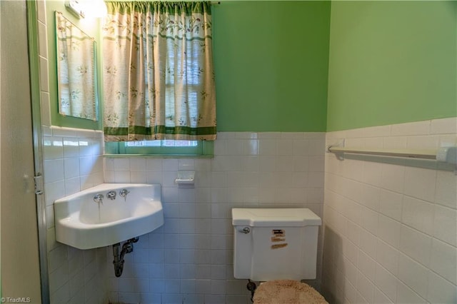 bathroom with toilet, tile walls, and sink