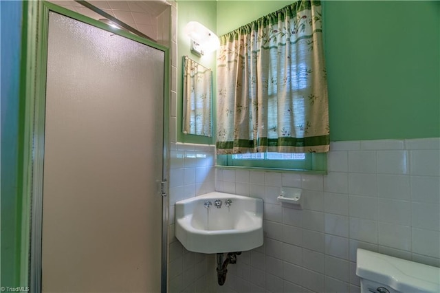 bathroom featuring toilet, sink, tile walls, and walk in shower