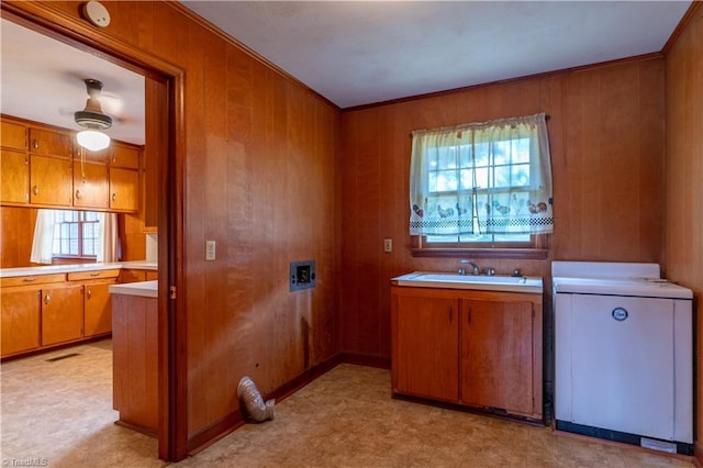 kitchen with wood walls, sink, ornamental molding, and washer / dryer