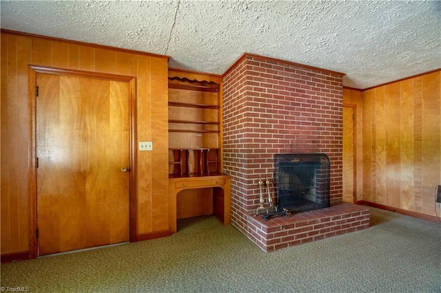 unfurnished living room with wooden walls, a brick fireplace, carpet flooring, ornamental molding, and a textured ceiling