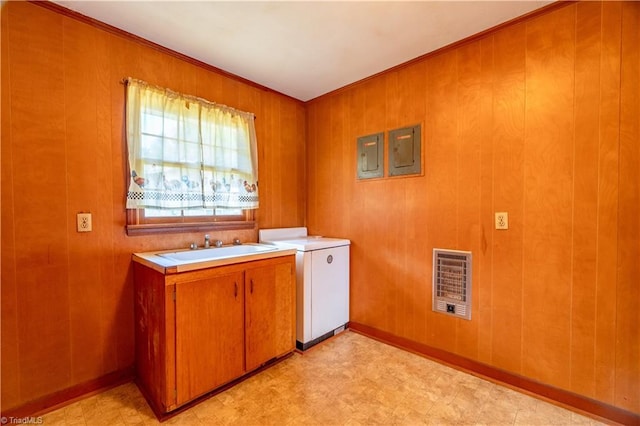 laundry room with cabinets, heating unit, sink, washer / dryer, and wood walls