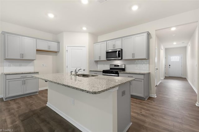 kitchen featuring sink, gray cabinetry, a center island with sink, appliances with stainless steel finishes, and decorative backsplash