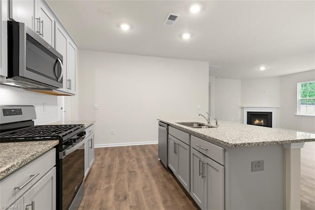 kitchen with sink, gray cabinetry, tasteful backsplash, a center island with sink, and appliances with stainless steel finishes