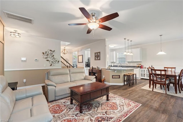 1951 Rubywood St, Greensboro, NC 27405 - living room featuring crown molding, a ceiling fan, dark wood finished floors, and stairs
