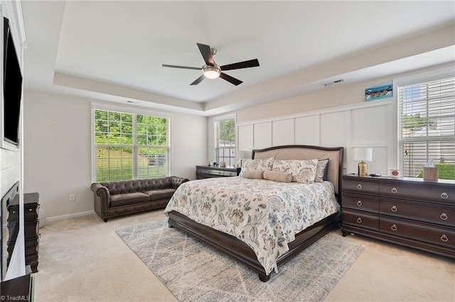 1951 Rubywood St, Greensboro, NC 27405 - bedroom featuring light carpet, a tray ceiling, a fireplace, and ceiling fan
