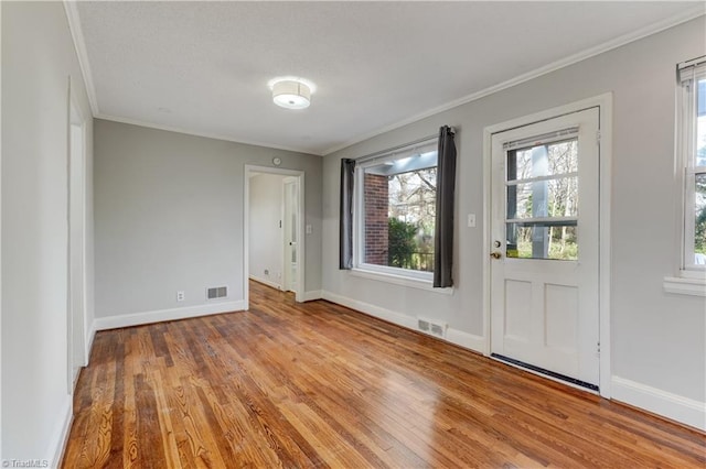 empty room with light hardwood / wood-style floors and crown molding