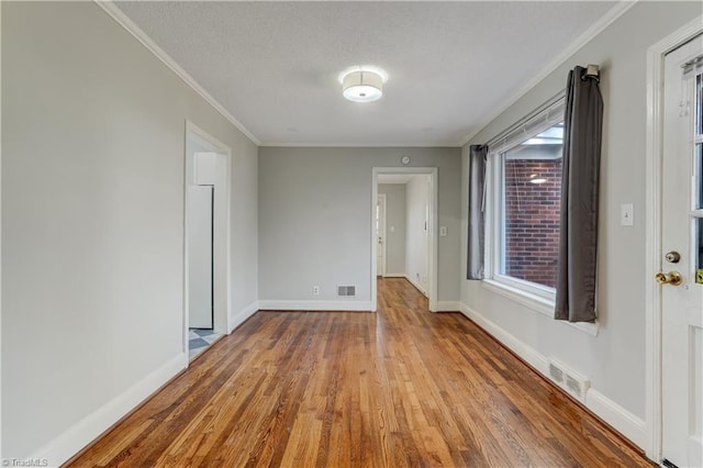 spare room with light wood-type flooring and crown molding