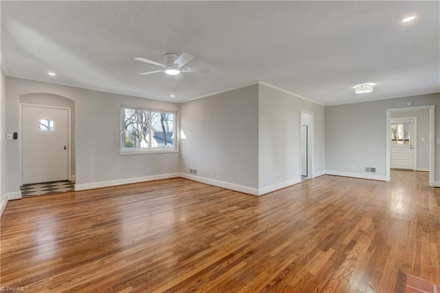 unfurnished living room with ceiling fan, ornamental molding, and wood-type flooring