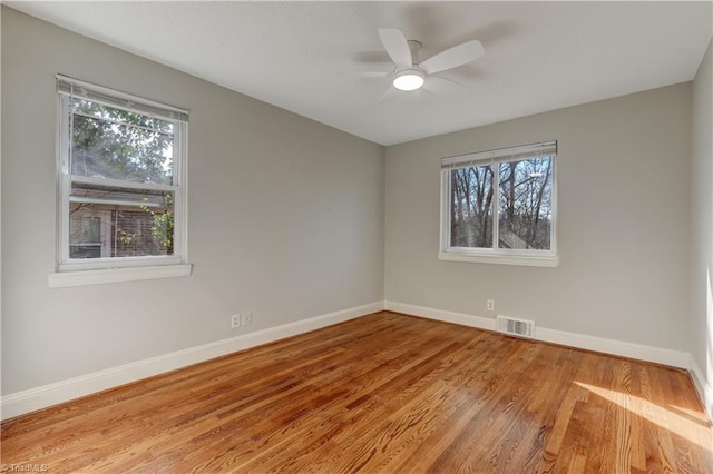 spare room featuring a healthy amount of sunlight, ceiling fan, and light hardwood / wood-style floors