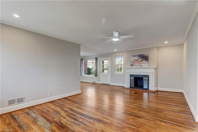 unfurnished living room featuring hardwood / wood-style flooring, ceiling fan, a textured ceiling, and ornamental molding