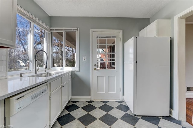 kitchen with white appliances, plenty of natural light, sink, and white cabinets