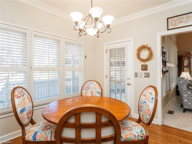 dining space with crown molding, a notable chandelier, and hardwood / wood-style flooring