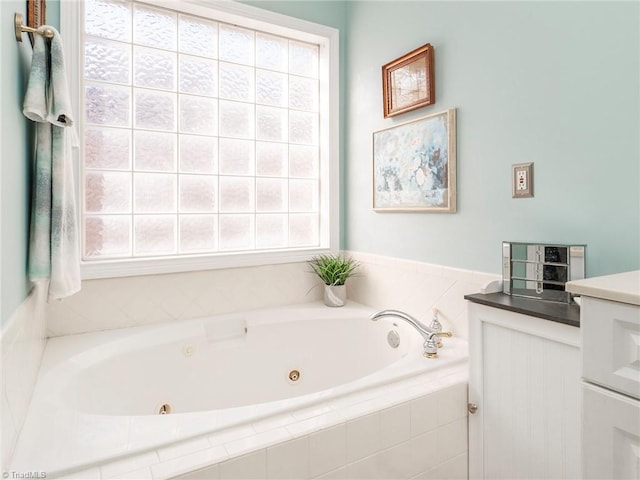 bathroom featuring vanity, a relaxing tiled tub, and a wealth of natural light