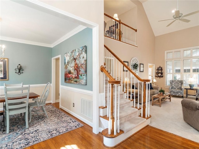 interior space with ornamental molding, ceiling fan with notable chandelier, hardwood / wood-style floors, and high vaulted ceiling