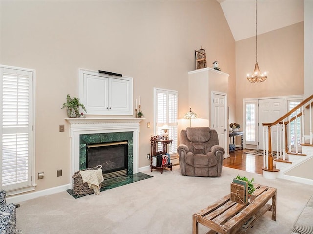 carpeted living room featuring a fireplace, high vaulted ceiling, a chandelier, and a healthy amount of sunlight