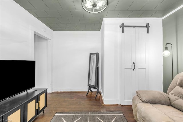 living area featuring dark wood-style floors, baseboards, and a barn door