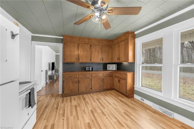 kitchen featuring white range, dark countertops, visible vents, brown cabinetry, and light wood-style floors