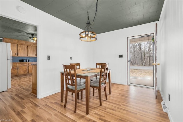 dining area featuring light wood finished floors, baseboards, and ceiling fan with notable chandelier