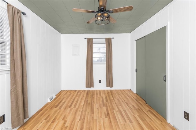 spare room featuring light wood-style floors, visible vents, and ceiling fan