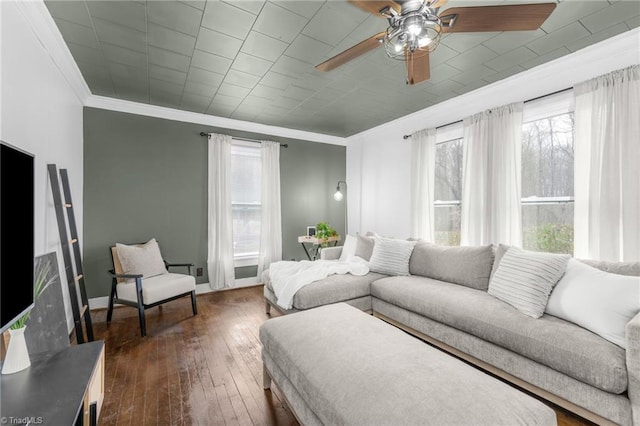 living area featuring dark wood-style floors, crown molding, baseboards, and ceiling fan