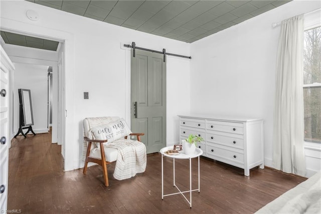 living area with a barn door and dark wood-style flooring