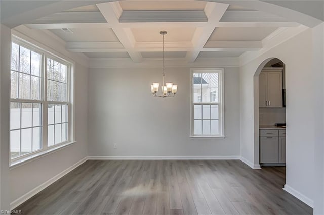 unfurnished dining area with an inviting chandelier, baseboards, coffered ceiling, and wood finished floors