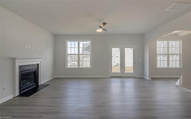 unfurnished living room featuring a fireplace with raised hearth, dark wood finished floors, visible vents, and baseboards