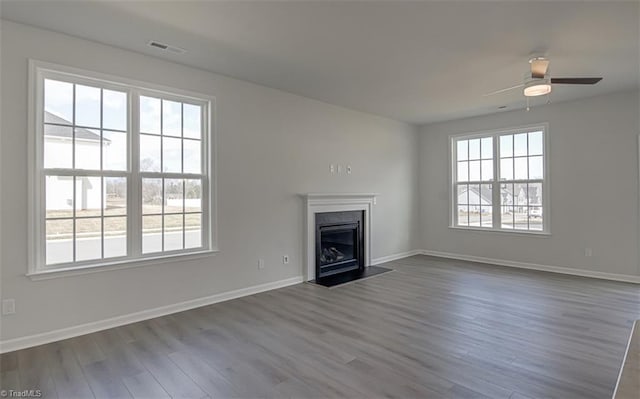 unfurnished living room featuring baseboards, a fireplace, visible vents, and dark wood-style flooring