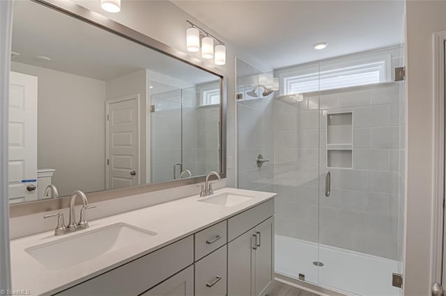 bathroom with double vanity, a stall shower, and a sink