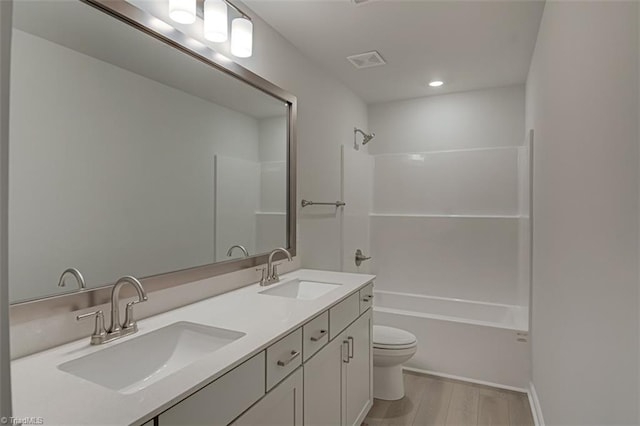 bathroom featuring toilet, visible vents, a sink, and wood finished floors