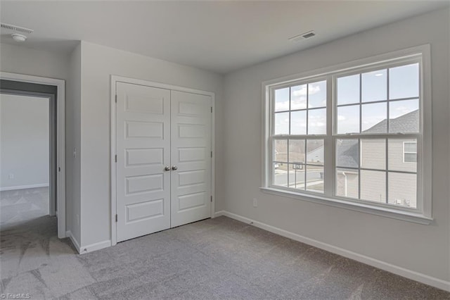 unfurnished bedroom with carpet floors, visible vents, and baseboards